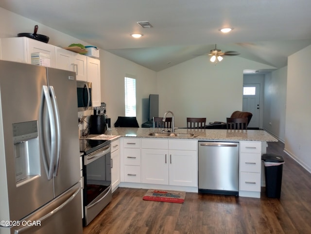 kitchen with light stone countertops, a peninsula, white cabinets, stainless steel appliances, and a sink