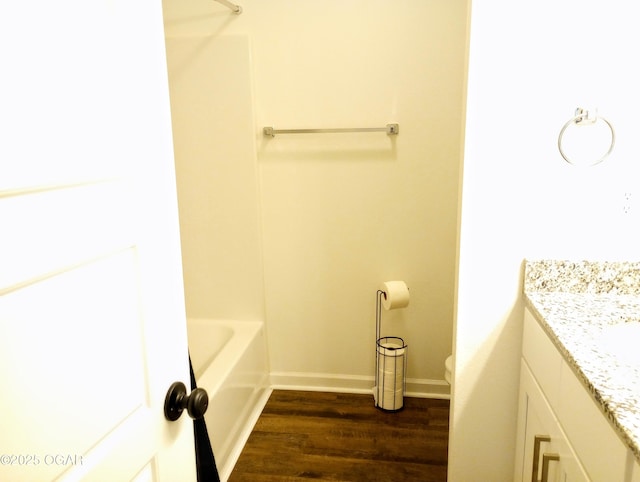 bathroom featuring baseboards, toilet, wood finished floors, and vanity