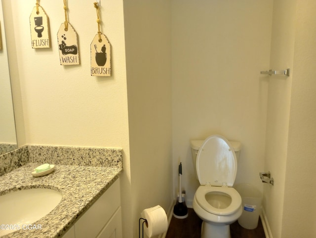 half bath featuring baseboards, toilet, and vanity