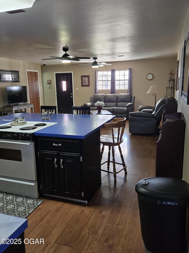 kitchen with dark wood-style floors, dark cabinets, electric range, a textured ceiling, and open floor plan