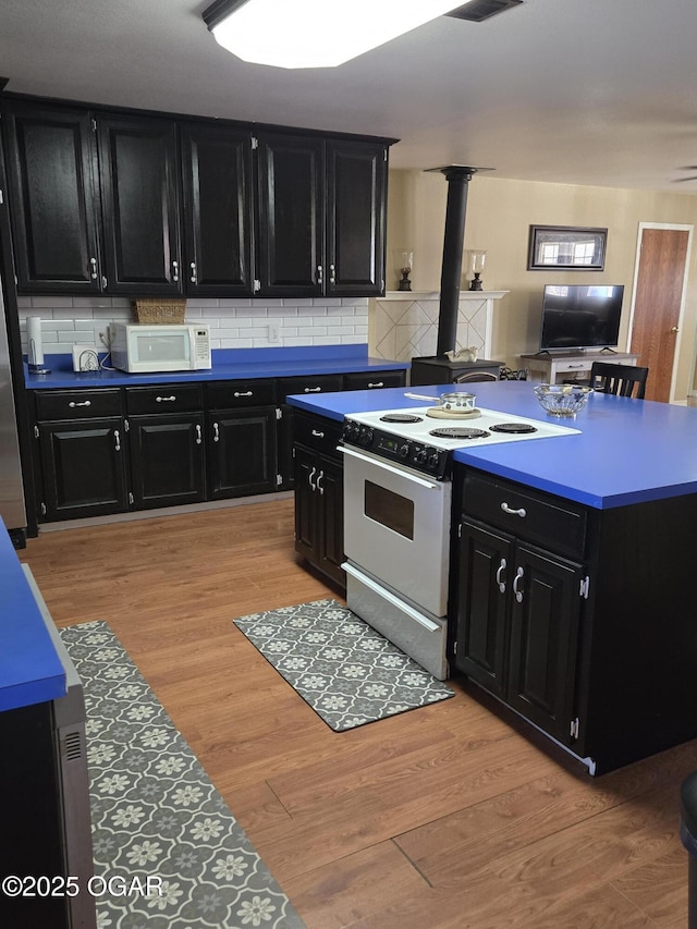 kitchen with light wood-type flooring, white appliances, tasteful backsplash, and dark cabinetry