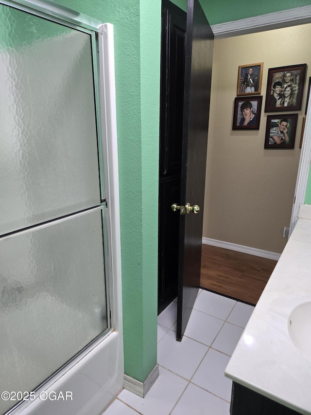 full bathroom with tile patterned flooring, double vanity, baseboards, and combined bath / shower with glass door