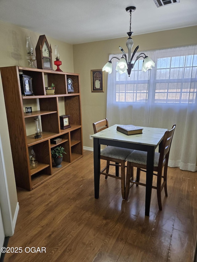 dining space with visible vents, baseboards, a chandelier, and dark wood-style flooring