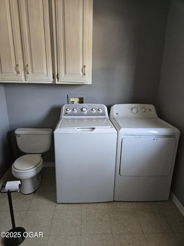 washroom featuring washer and dryer, laundry area, light tile patterned floors, and baseboards