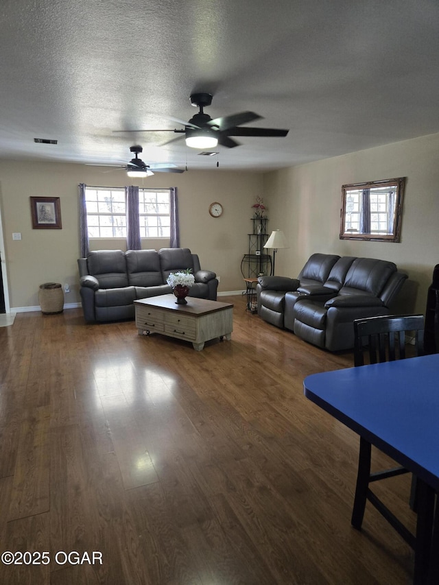 living area with a wealth of natural light, a textured ceiling, and wood finished floors