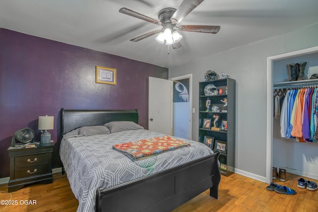 bedroom with a ceiling fan, wood finished floors, baseboards, and a closet