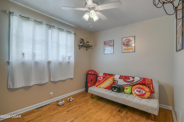 living area with visible vents, wood-type flooring, baseboards, and ceiling fan