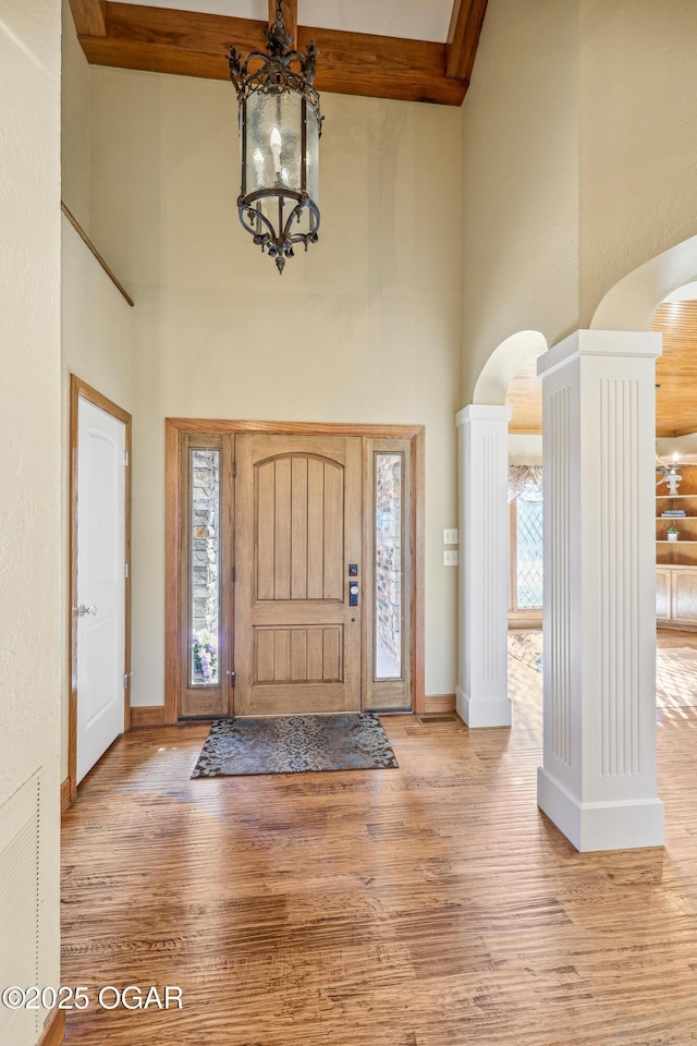 entrance foyer featuring visible vents, wood finished floors, arched walkways, baseboards, and a towering ceiling