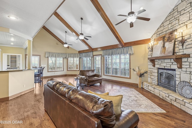 living area featuring ceiling fan, beam ceiling, a fireplace, wood finished floors, and high vaulted ceiling