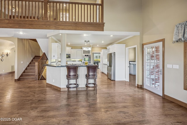 kitchen with dark countertops, crown molding, dark wood finished floors, white cabinets, and stainless steel appliances