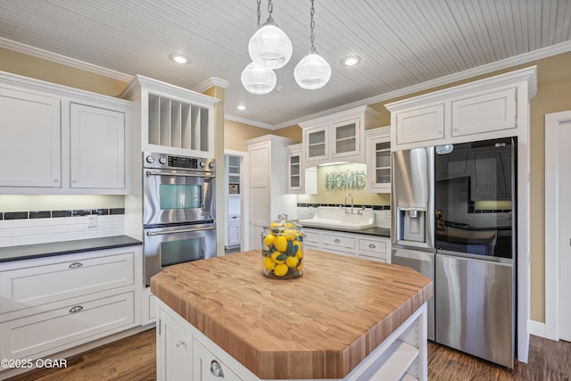 kitchen featuring a kitchen island, a sink, decorative backsplash, ornamental molding, and stainless steel appliances