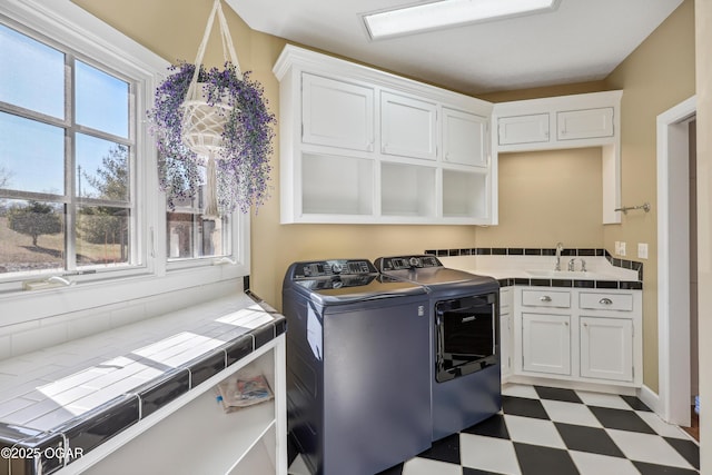 laundry area featuring tile patterned floors, cabinet space, a sink, and washer and clothes dryer