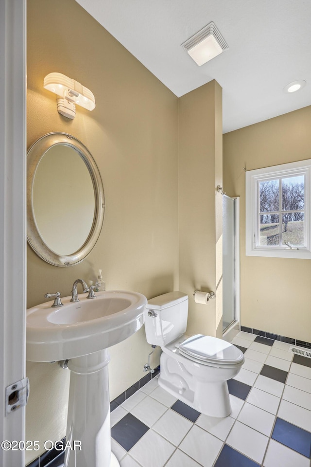 bathroom with tile patterned floors, visible vents, toilet, and a shower stall