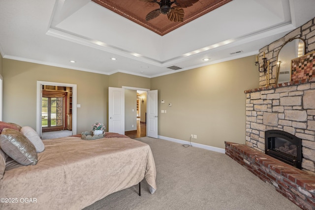 bedroom with visible vents, baseboards, carpet floors, a stone fireplace, and a raised ceiling