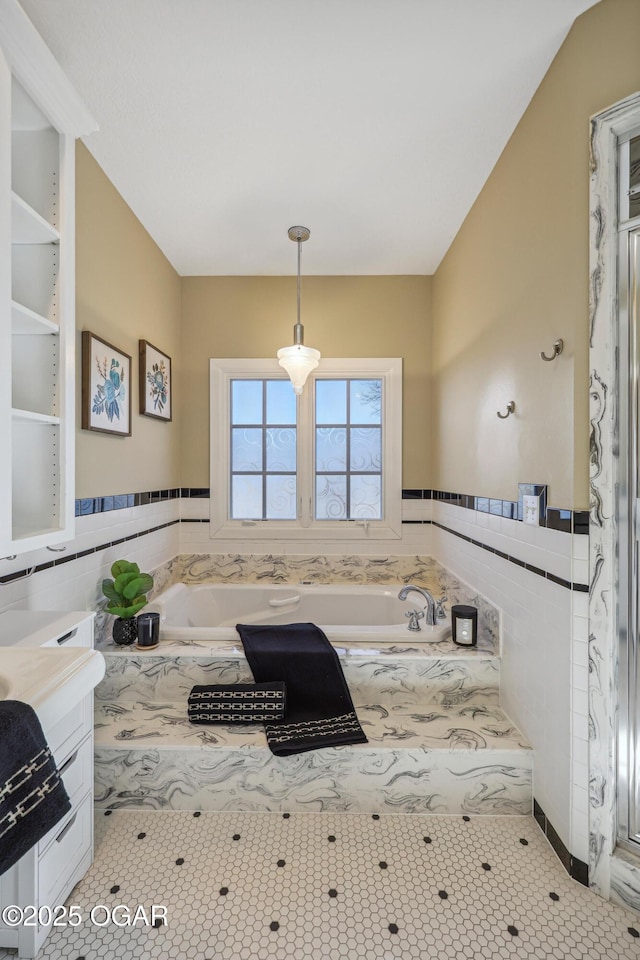 bathroom with vanity, tile walls, and a bath