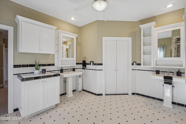 kitchen with white cabinetry, tile counters, a wainscoted wall, and ceiling fan