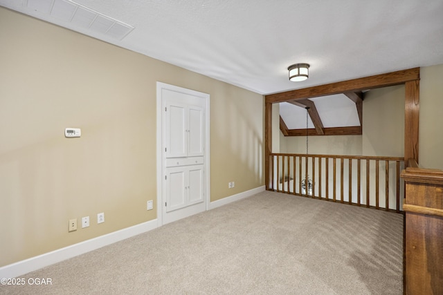 carpeted empty room featuring vaulted ceiling with skylight, visible vents, and baseboards