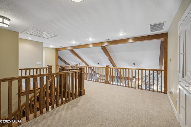 corridor featuring visible vents, a textured ceiling, vaulted ceiling with beams, and carpet floors