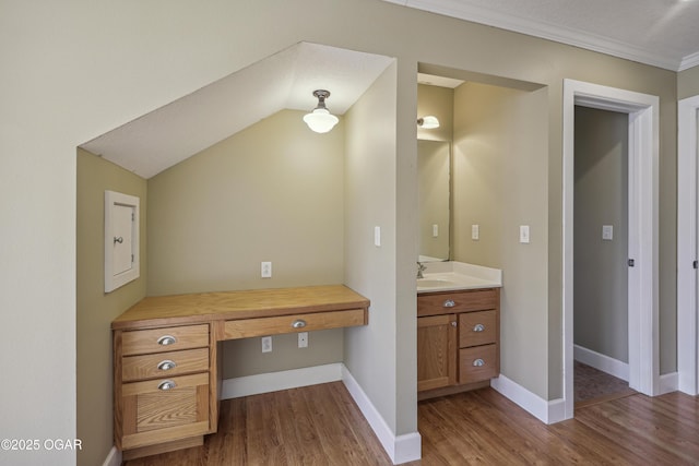 bathroom featuring baseboards, wood finished floors, vanity, and crown molding