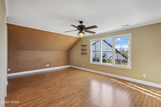 additional living space with visible vents, baseboards, lofted ceiling, wood finished floors, and a ceiling fan