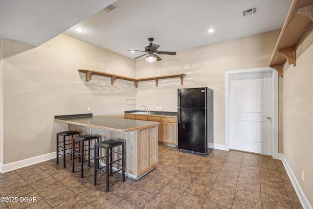 kitchen featuring a breakfast bar, a ceiling fan, open shelves, dark countertops, and freestanding refrigerator