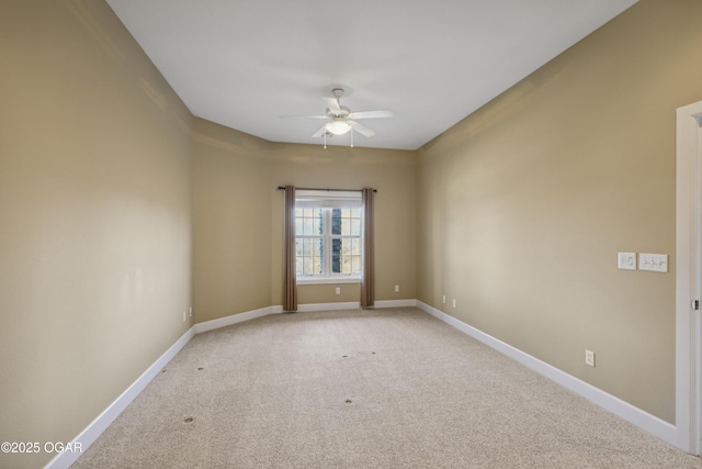 spare room featuring light colored carpet, baseboards, and ceiling fan