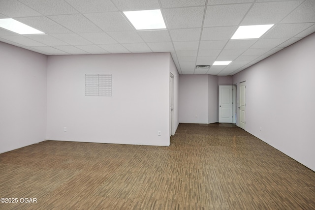 unfurnished room with wood finished floors, visible vents, and a paneled ceiling