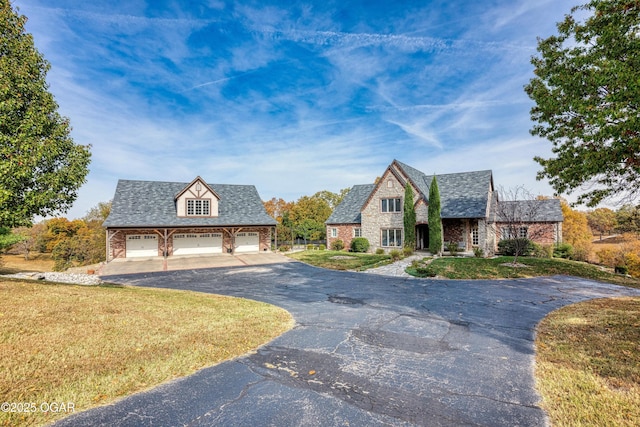 view of front of house featuring aphalt driveway, stone siding, an outdoor structure, a front yard, and a garage