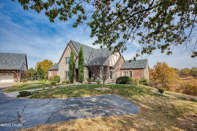 tudor house with a front yard and stone siding