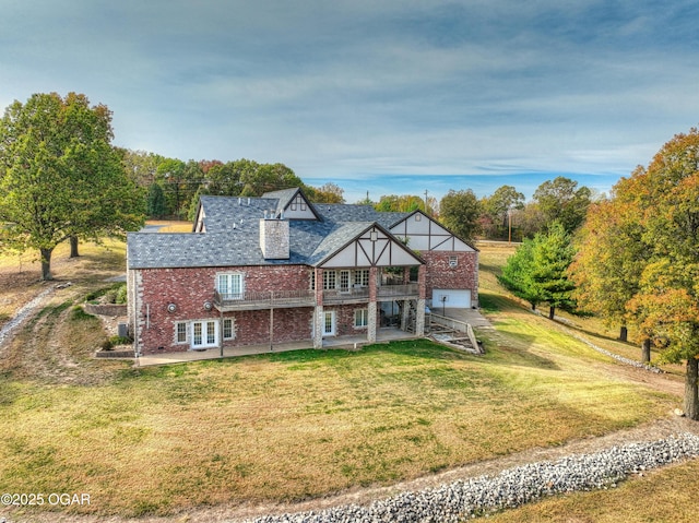 view of front of home with brick siding, a patio, french doors, and a front yard