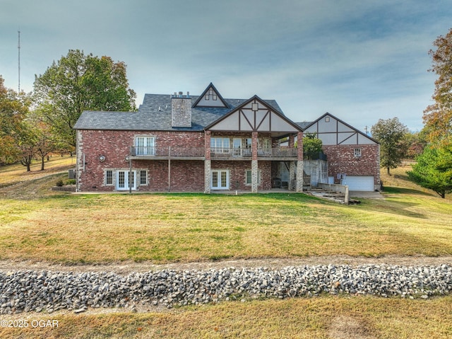 back of property with brick siding, a garage, and a yard