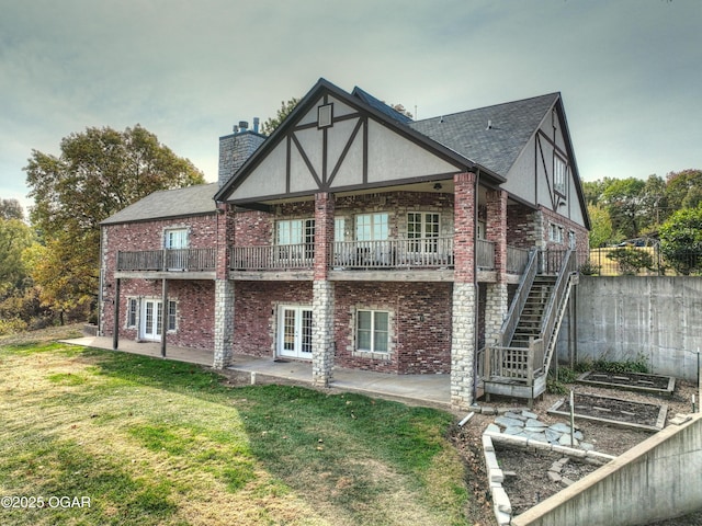 rear view of property featuring a vegetable garden, a chimney, french doors, a patio area, and a lawn