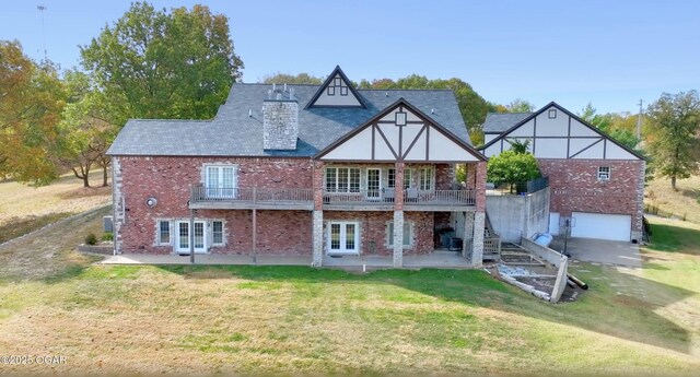 back of property with french doors, a yard, a garage, brick siding, and stairs