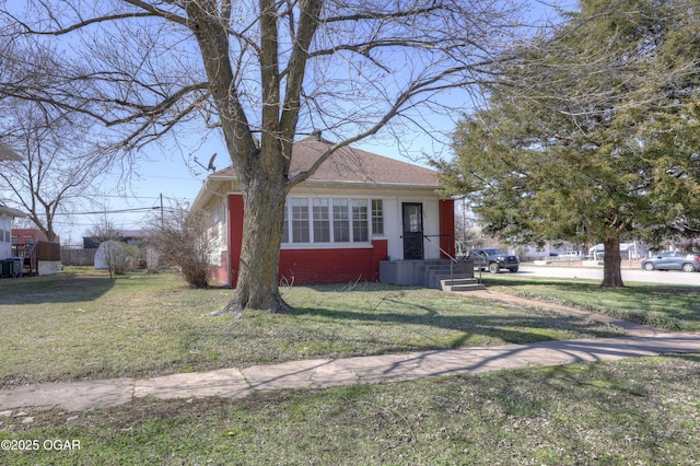 bungalow-style home with a front yard, brick siding, and roof with shingles