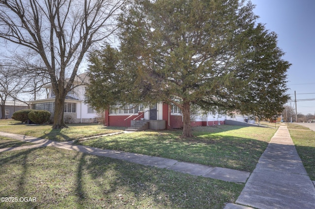 view of property hidden behind natural elements with brick siding and a front yard