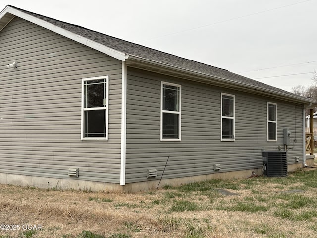 view of side of home featuring central air condition unit and roof with shingles