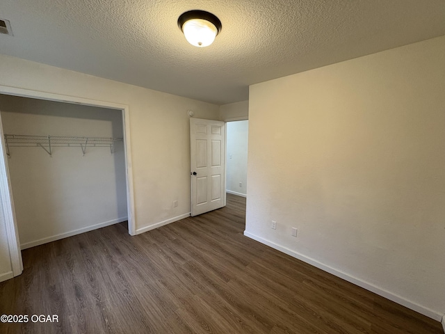 unfurnished bedroom with visible vents, baseboards, dark wood-style flooring, a closet, and a textured ceiling