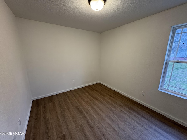 empty room featuring dark wood finished floors, baseboards, and a textured ceiling