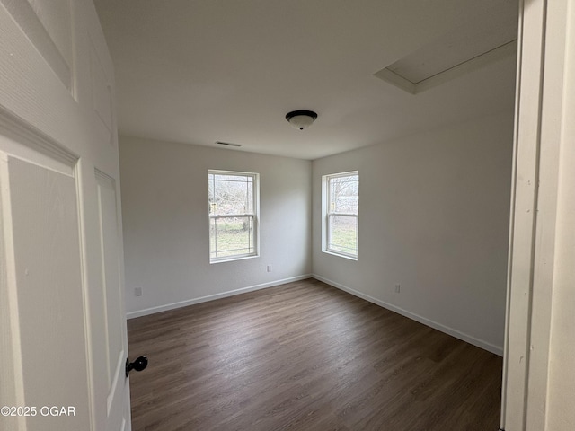 unfurnished room featuring visible vents, baseboards, and dark wood-style flooring