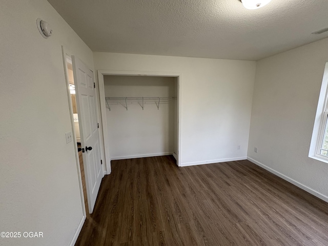 unfurnished bedroom featuring visible vents, baseboards, dark wood finished floors, a closet, and a textured ceiling