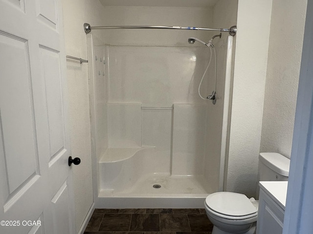 full bath with toilet, walk in shower, vanity, and a textured wall