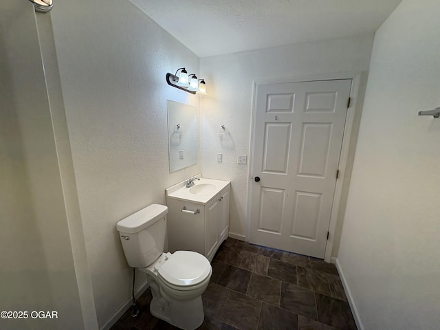 bathroom featuring vanity, toilet, and baseboards