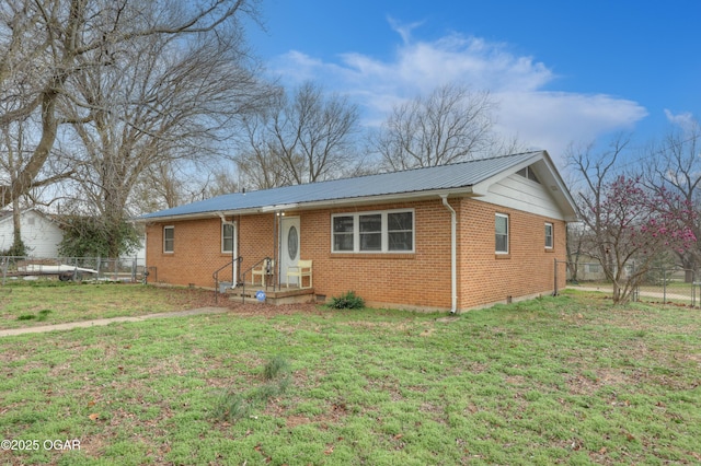 ranch-style home with metal roof, brick siding, a front lawn, and fence