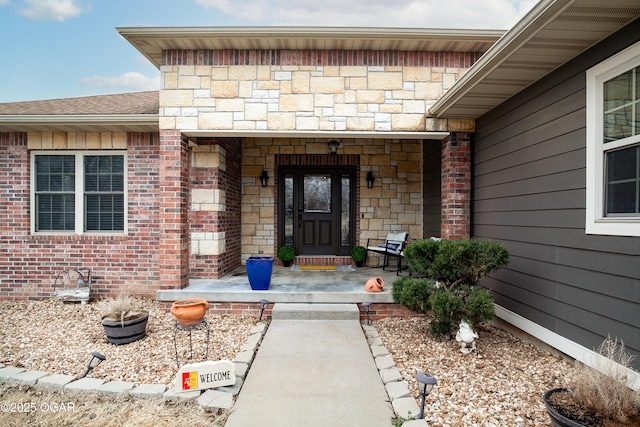 view of exterior entry featuring a porch, brick siding, and stone siding