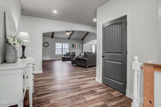foyer entrance featuring a ceiling fan, wood finished floors, baseboards, vaulted ceiling with beams, and arched walkways