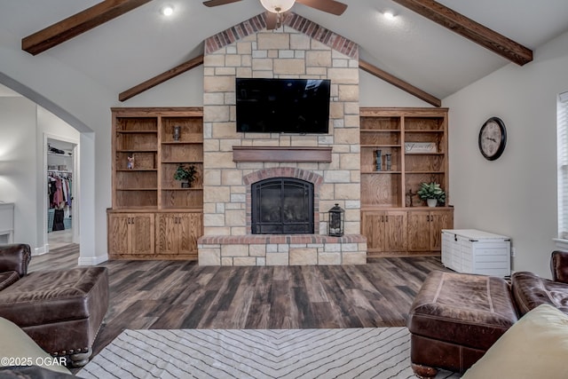 living area with a stone fireplace, wood finished floors, vaulted ceiling with beams, and a ceiling fan