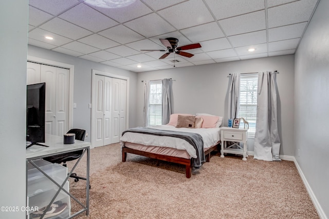 bedroom featuring multiple closets, a drop ceiling, recessed lighting, carpet floors, and baseboards