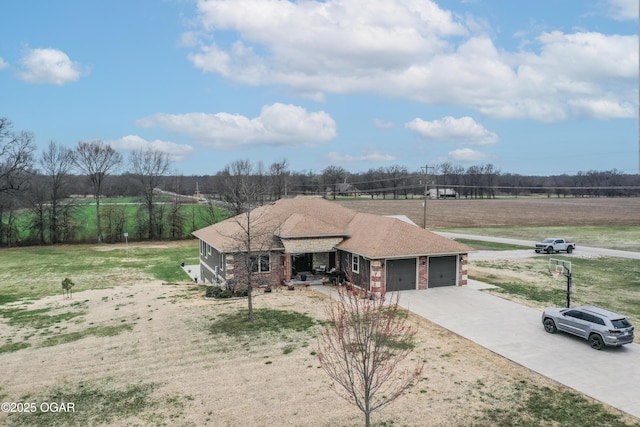 view of front facade featuring brick siding, a rural view, a shingled roof, concrete driveway, and an attached garage