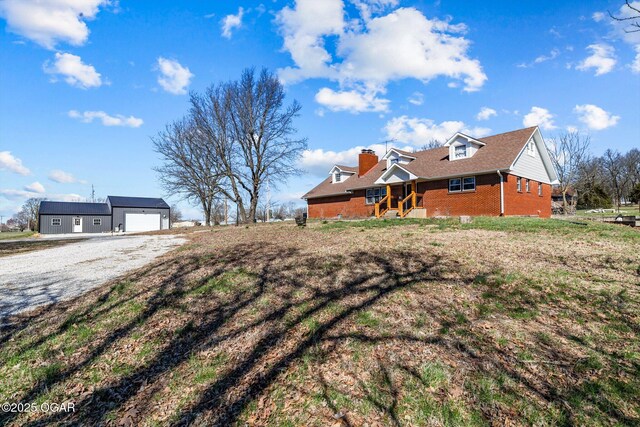 9426 Business 60, Monett, MO 65708 - exterior space featuring a chimney, an outbuilding, brick siding, gravel driveway, and a garage