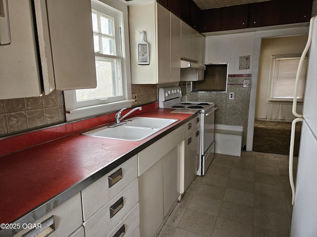 906 Randolph St, Neosho, MO 64850 - kitchen featuring a sink, under cabinet range hood, white appliances, dark countertops, and white cabinets